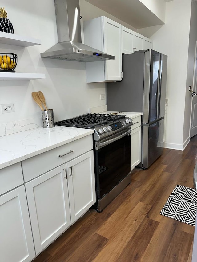 kitchen with dark hardwood / wood-style flooring, stainless steel appliances, white cabinets, light stone counters, and wall chimney exhaust hood