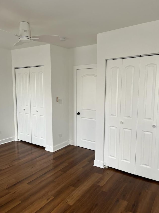 unfurnished bedroom featuring two closets, ceiling fan, and dark hardwood / wood-style flooring