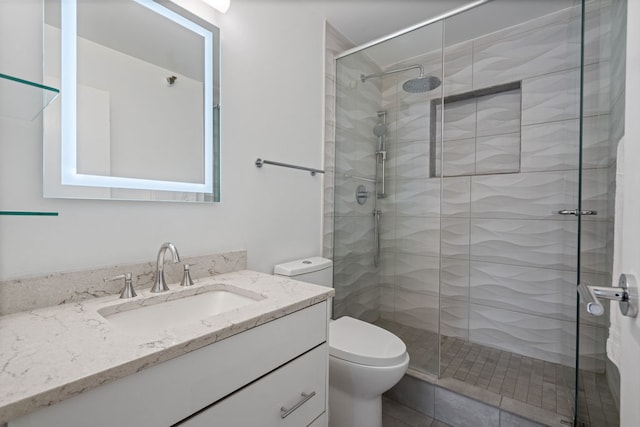 bathroom featuring a shower with shower door, toilet, and vanity