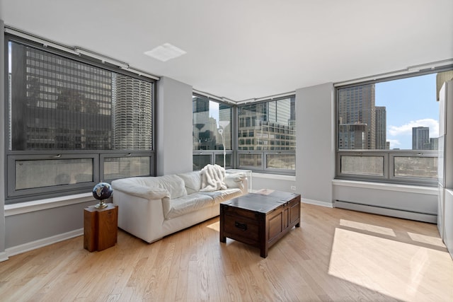 living room featuring a healthy amount of sunlight, a baseboard heating unit, and light hardwood / wood-style flooring