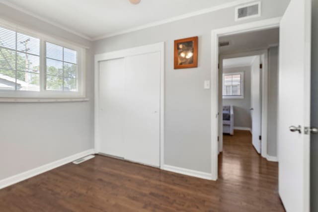 unfurnished bedroom featuring ornamental molding, dark hardwood / wood-style floors, and a closet