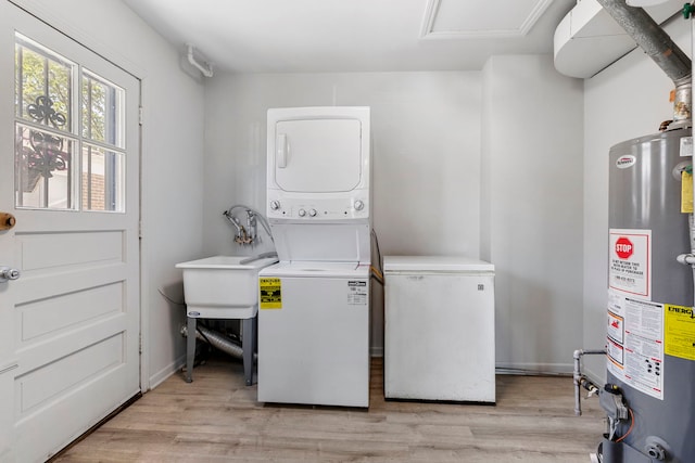 washroom with stacked washing maching and dryer, sink, light hardwood / wood-style flooring, and water heater