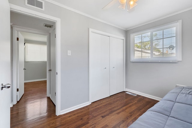 bedroom featuring dark hardwood / wood-style floors, ceiling fan, a closet, and crown molding