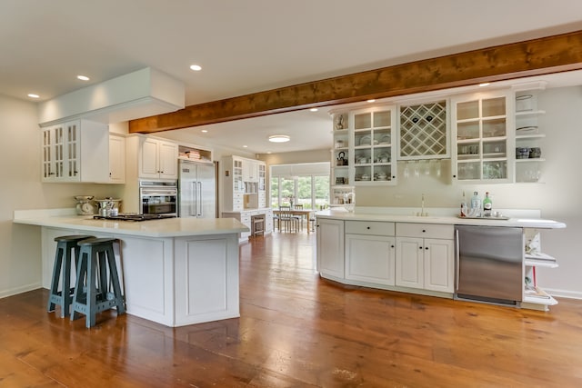 kitchen featuring light hardwood / wood-style floors, a breakfast bar area, white cabinetry, kitchen peninsula, and appliances with stainless steel finishes