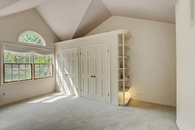 unfurnished bedroom featuring light carpet and lofted ceiling