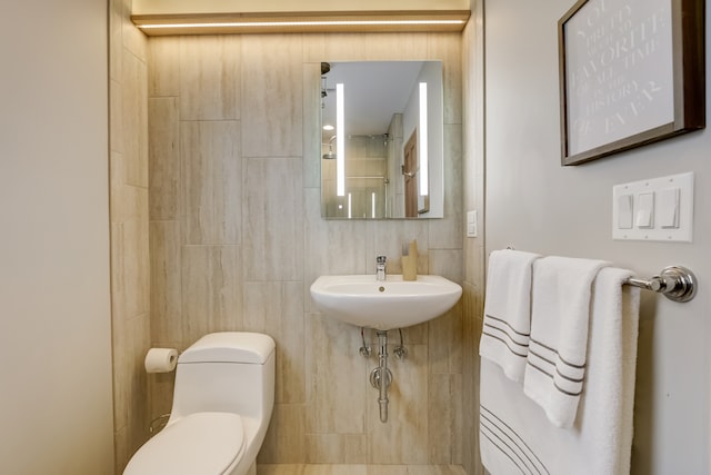 bathroom with tile walls, sink, and toilet