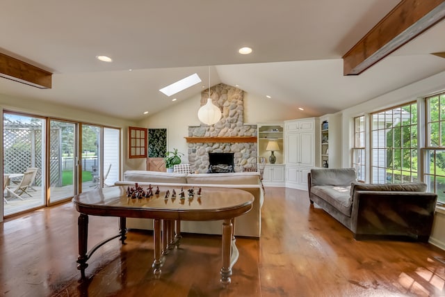 dining area with hardwood / wood-style flooring, a stone fireplace, a skylight, and plenty of natural light