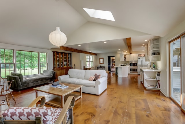 living room with a skylight, light wood-type flooring, and high vaulted ceiling