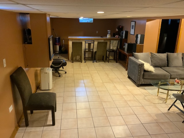 living room with light tile flooring and a paneled ceiling