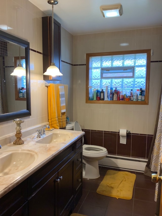 bathroom featuring toilet, vanity with extensive cabinet space, tile walls, and a baseboard heating unit