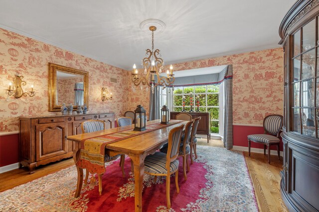 dining space featuring a notable chandelier, ornamental molding, and light wood-type flooring