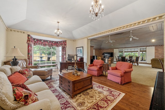 carpeted living room featuring lofted ceiling, brick wall, and ceiling fan with notable chandelier