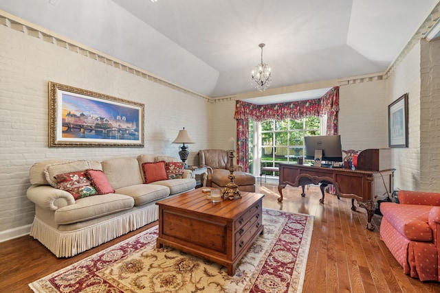 living room featuring lofted ceiling, hardwood / wood-style flooring, brick wall, and a chandelier