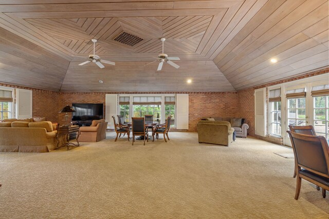 carpeted living room with wooden ceiling, a wealth of natural light, and brick wall