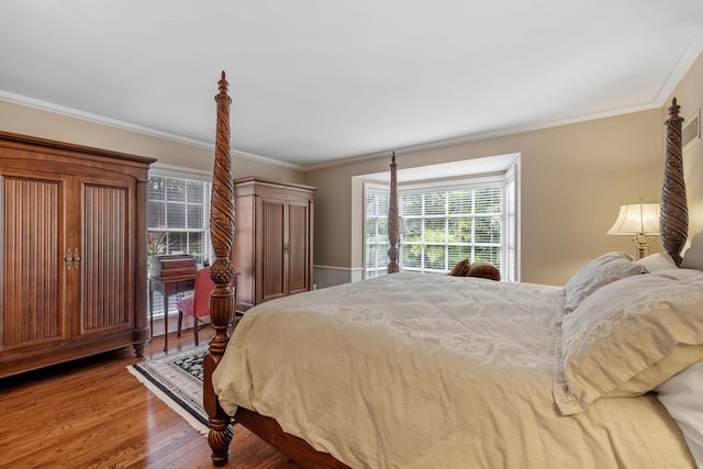 bedroom with ornamental molding and wood finished floors