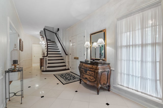 entrance foyer featuring tile patterned floors, crown molding, and stairs