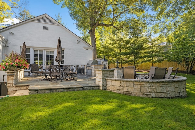 rear view of house with a patio, a lawn, an outdoor kitchen, and fence