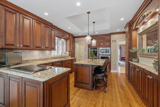 kitchen with light hardwood / wood-style floors, decorative light fixtures, stainless steel microwave, a center island, and sink