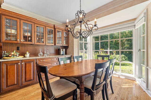 dining room featuring ornamental molding, an inviting chandelier, and light wood-type flooring