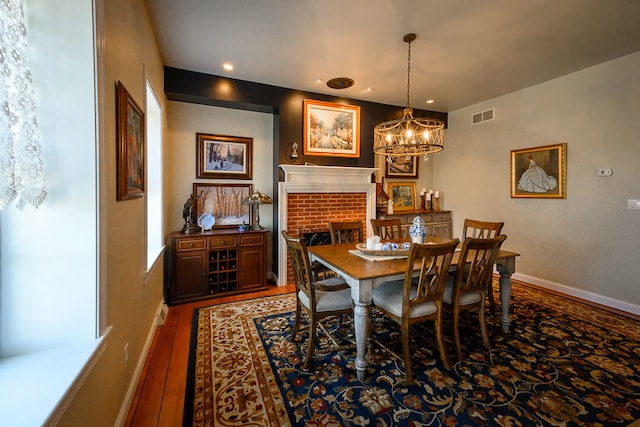 dining room with hardwood / wood-style flooring, a fireplace, and a chandelier
