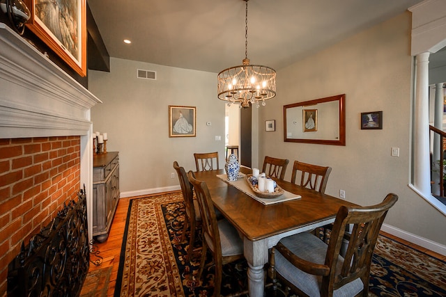 dining area with dark hardwood / wood-style floors, an inviting chandelier, and ornate columns