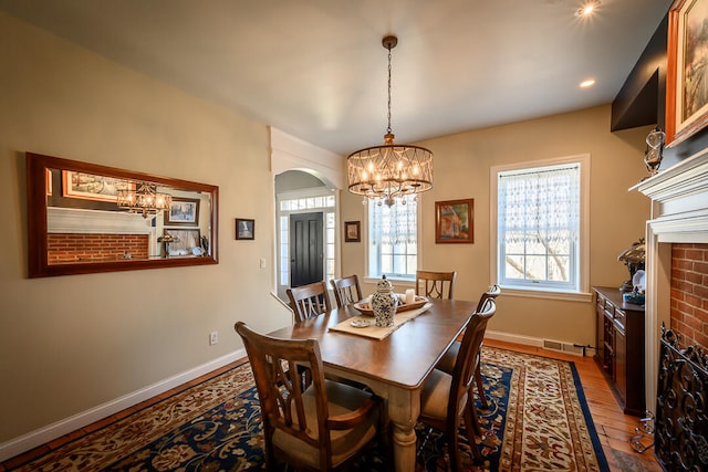 dining space with a fireplace, wood-type flooring, and a chandelier