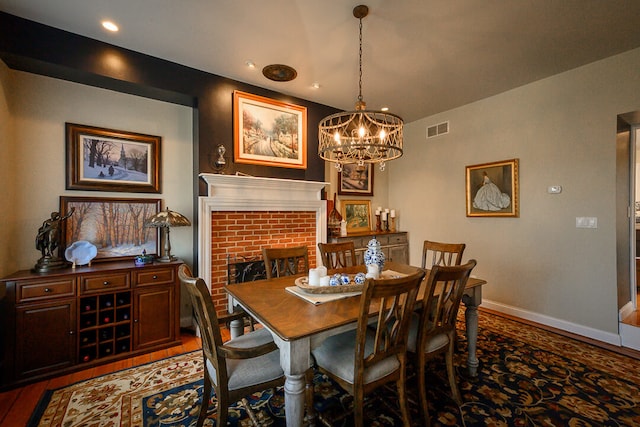 dining area with hardwood / wood-style flooring, a fireplace, and an inviting chandelier