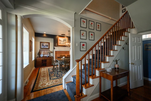 stairway featuring wood-type flooring and decorative columns