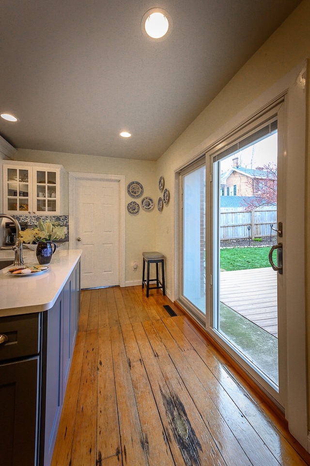 kitchen with white cabinets, light hardwood / wood-style floors, and tasteful backsplash