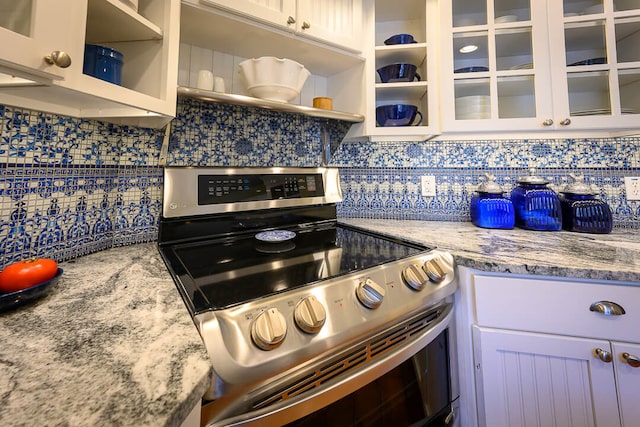 kitchen with decorative backsplash, white cabinets, light stone countertops, and electric stove