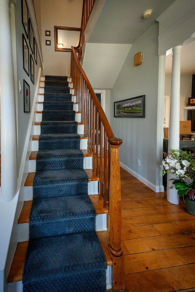 stairway with wood-type flooring and decorative columns