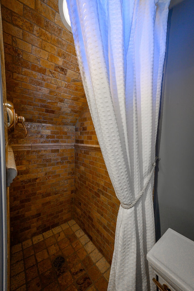 bathroom with a shower, lofted ceiling, brick ceiling, and brick wall