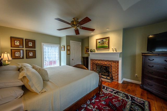 bedroom with a fireplace, dark hardwood / wood-style flooring, and ceiling fan