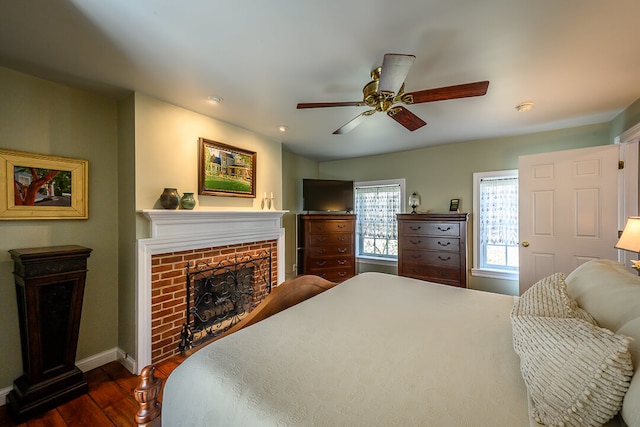 bedroom with ceiling fan, dark hardwood / wood-style flooring, and a fireplace