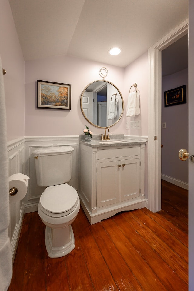 bathroom featuring vanity, wood-type flooring, vaulted ceiling, and toilet