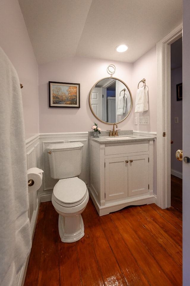 bathroom with hardwood / wood-style floors, vanity, toilet, and lofted ceiling