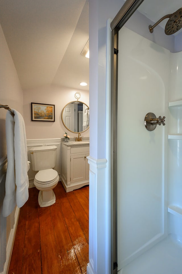 bathroom featuring hardwood / wood-style floors, vanity, vaulted ceiling, toilet, and walk in shower