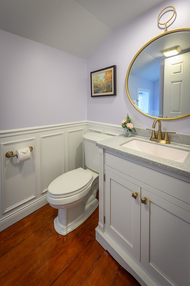 bathroom with hardwood / wood-style floors, vanity, toilet, and lofted ceiling