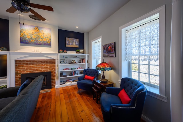 interior space with ceiling fan, hardwood / wood-style floors, and a brick fireplace