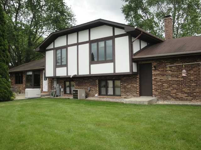 rear view of house featuring a lawn and central air condition unit