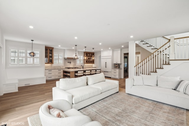 living room featuring ceiling fan, light hardwood / wood-style flooring, and sink