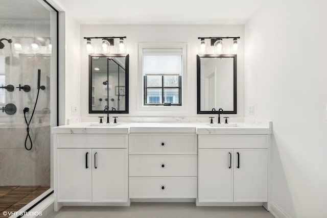 bathroom featuring tiled shower and double sink vanity