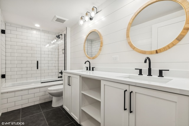 full bathroom featuring tile flooring, double vanity, toilet, and bath / shower combo with glass door