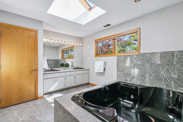 bathroom featuring a sink, visible vents, a tub with jets, and a wealth of natural light