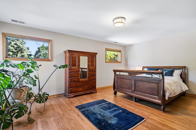 bedroom with light wood-style flooring, visible vents, and baseboards