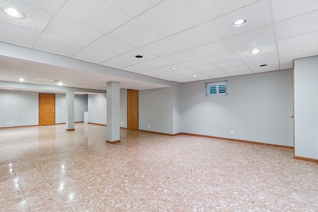 finished basement with a paneled ceiling, baseboards, and recessed lighting