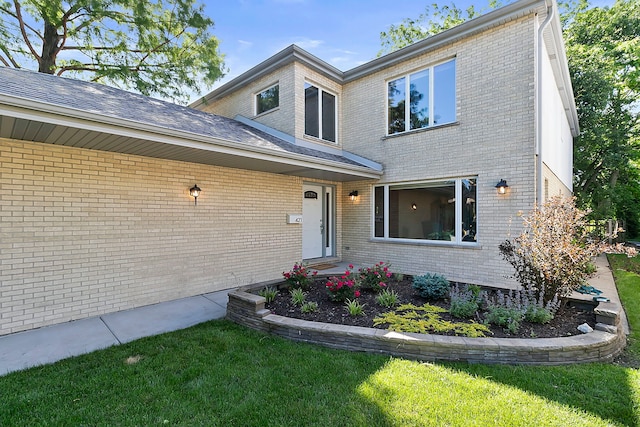 view of front facade with brick siding and a front lawn