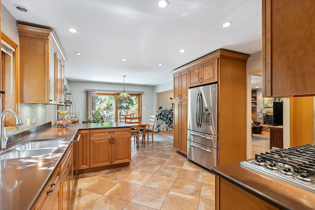 kitchen with light tile patterned floors, stainless steel appliances, dark countertops, a sink, and a peninsula