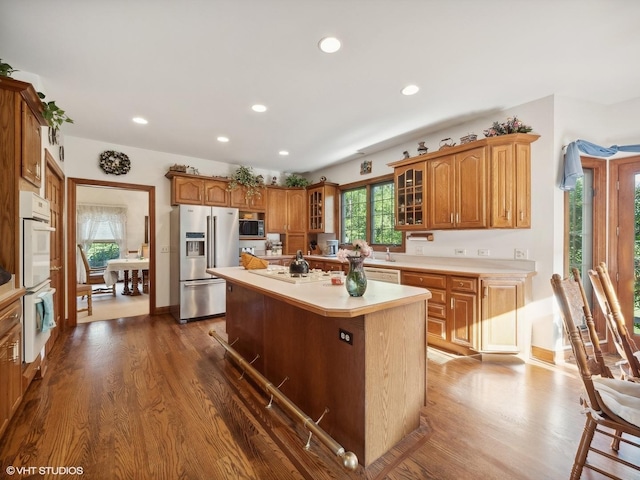 kitchen with dark wood-type flooring, appliances with stainless steel finishes, and a kitchen island with sink