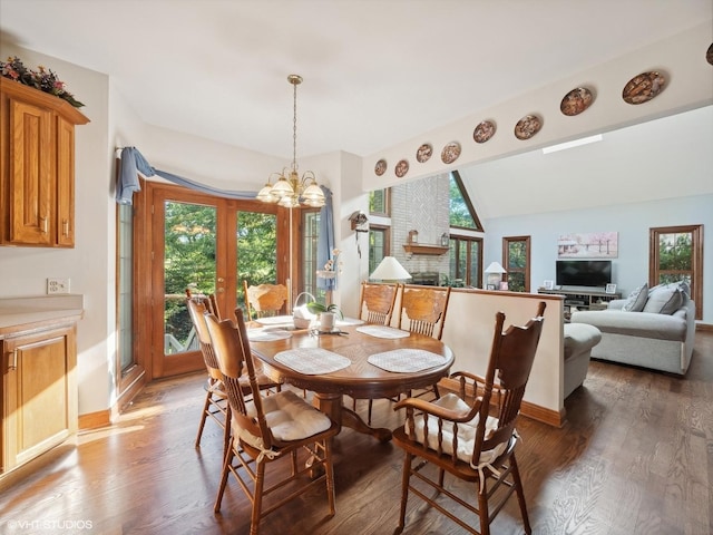 dining space with vaulted ceiling, an inviting chandelier, and dark hardwood / wood-style flooring